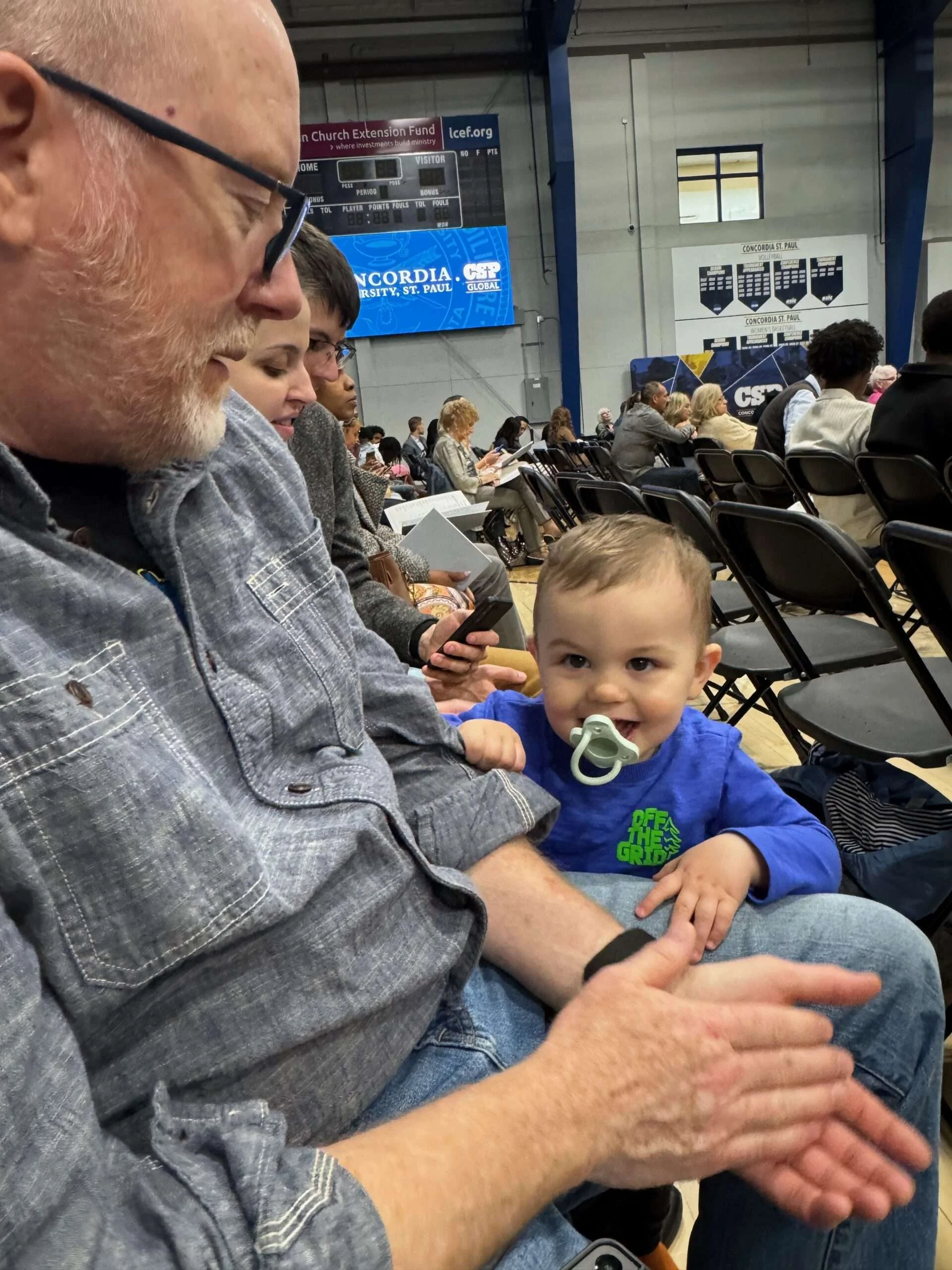 Grandfather holding and smiling at a young child, illustrating the secure attachment that helps children develop trust and emotional safety.